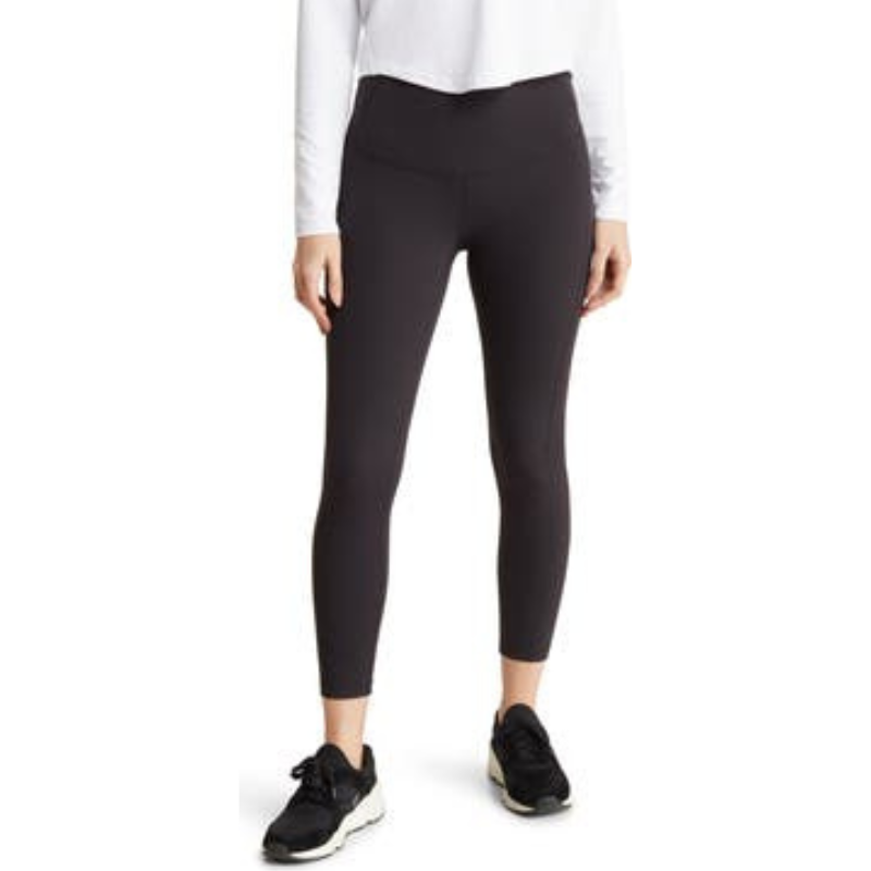High-waisted black leggings with an ankle-length fit, paired with black and white athletic shoes.