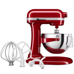 A red stand mixer with a stainless steel bowl, accompanied by three attachments: a whisk, a flat beater, and a dough hook.
