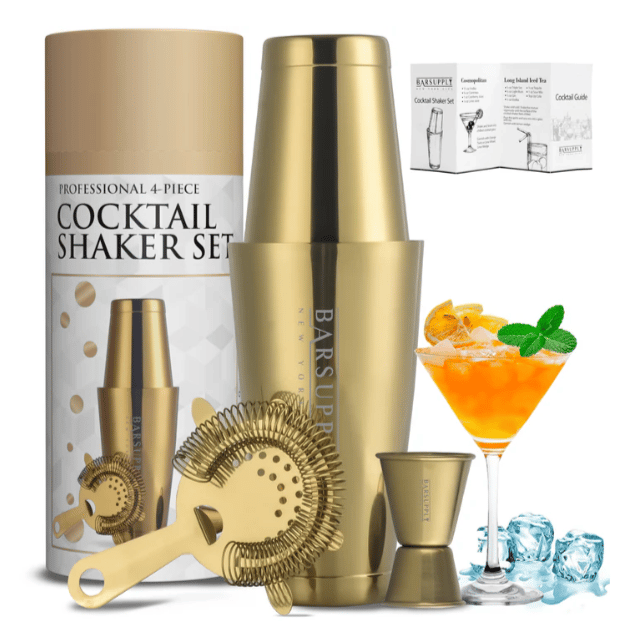 4-piece gold cocktail shaker set with shaker, strainer, jigger, and a recipe guide. Decorated with an orange cocktail garnish and ice cubes.