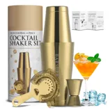 4-piece gold cocktail shaker set with shaker, strainer, jigger, and a recipe guide. Decorated with an orange cocktail garnish and ice cubes.