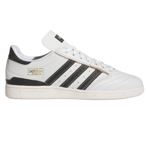 Adidas Busenitz sneakers, featuring a white leather upper with black stripes, gold branding, and a textured sole.