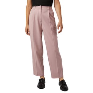 A pair of pink tailored trousers with a high waist, front pleats, and ankle length, worn with black loafers and a black top.
