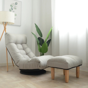 A cushioned lounge chair with matching ottoman, set on a wooden floor, next to a lamp and a potted plant in a softly lit room.