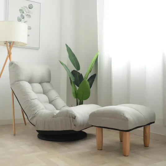 A cushioned lounge chair with matching ottoman, set on a wooden floor, next to a lamp and a potted plant in a softly lit room.