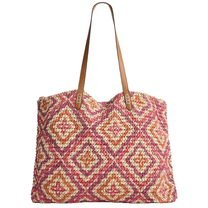 A woven tote bag with a pink, peach, and white diamond pattern featuring brown leather handles.
