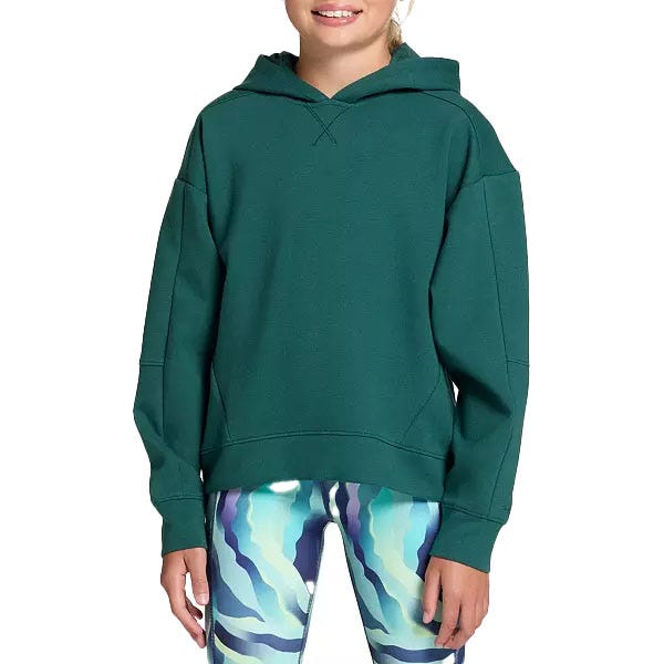 A person wearing a dark green hoodie paired with patterned leggings displaying a wavy blue and purple design.