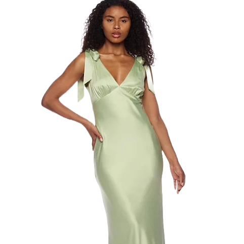 A woman is wearing a light green, satin slip dress with a V-neck, tie shoulder straps, and a form-fitting silhouette.