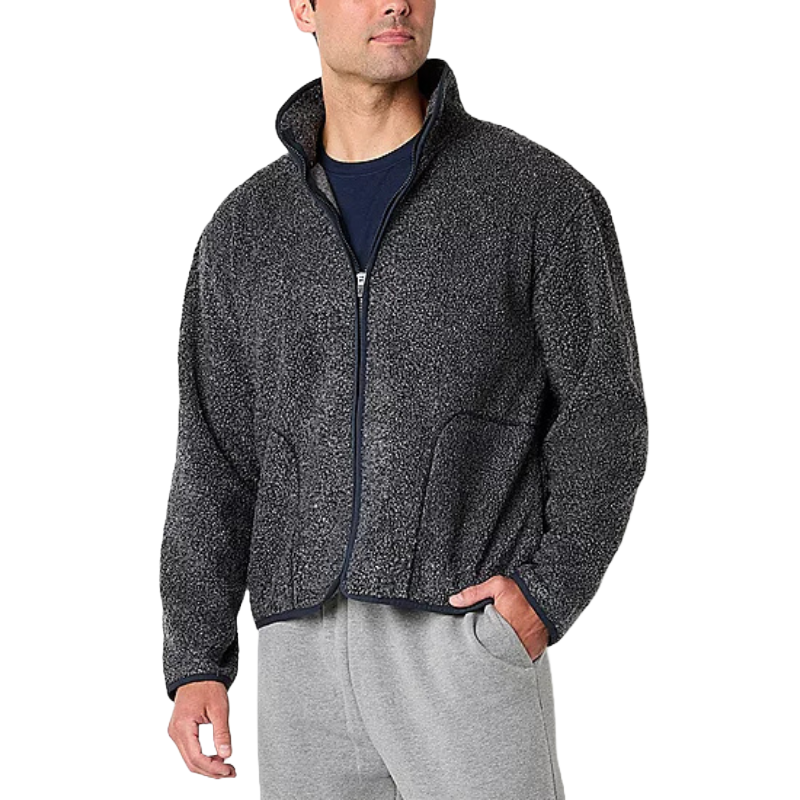 A man is wearing a zip-up, textured dark gray fleece jacket with a high collar, along with light gray sweatpants.