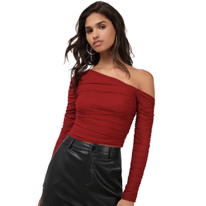 A woman wears a red, off-the-shoulder, long-sleeve crop top with small embellishments, paired with high-waisted black leather pants.