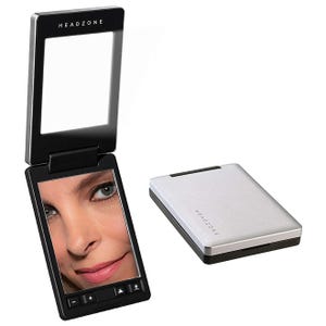 A compact LED makeup mirror with a foldable design, featuring adjustable brightness controls. The closed version is a sleek silver finish with the brand name \“HEADZONE\“ on the top.
