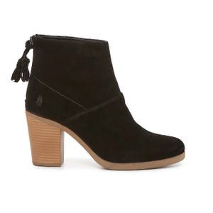 A black suede ankle boot with a tasseled zipper and stacked wooden heel.