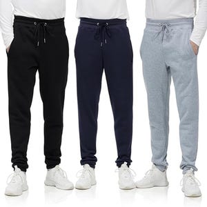 Three pairs of sweatpants in black, navy, and light gray, each with drawstrings and side pockets, worn with white sneakers.