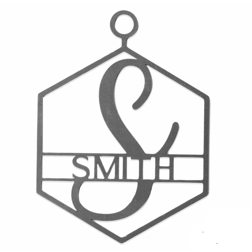 A hexagonal steel ornament featuring a large stylized letter \“E\“ intertwined with the word \“SMITH\“ etched across the center.
