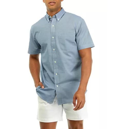 A man wearing a blue button-up shirt and white shorts.