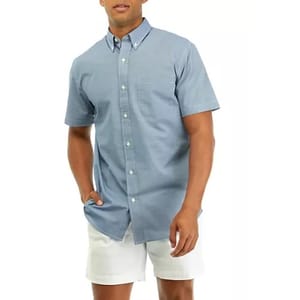 A man wearing a blue button-up shirt and white shorts.