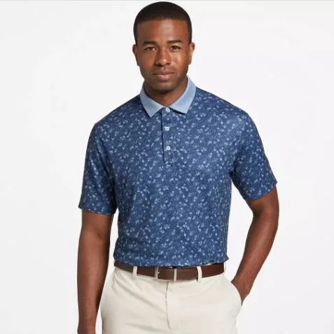 Man wearing a blue floral patterned polo shirt and khaki pants with a brown belt.