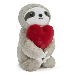 A plush sloth toy with a soft gray and white body holds a plush red heart.