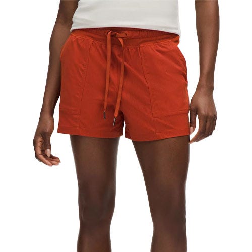 Rust-colored women's shorts with an elastic waistband and drawstring, featuring two side pockets. Worn with a white top.
