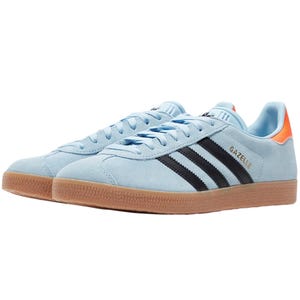 Light blue Adidas Gazelle sneakers with black stripes, orange heel accents, and a gum sole.