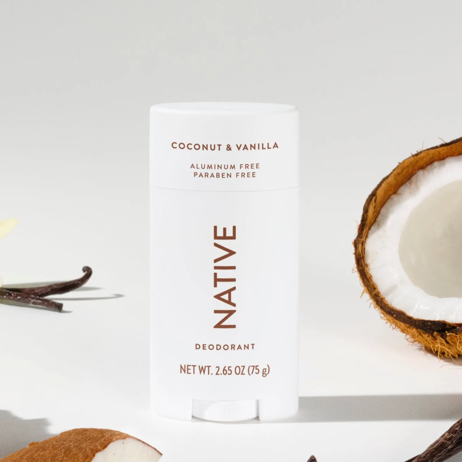 Native Coconut & Vanilla deodorant, 2.65 oz (75 g), is shown with pieces of coconut, vanilla beans, and a vanilla flower. The product is aluminum-free and paraben-free.
