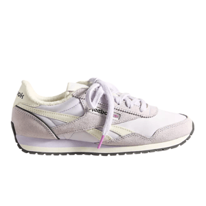 A lavender and white Reebok Classic shoe with suede and leather detailing, featuring a soft plush lining and a black and white rubber sole.