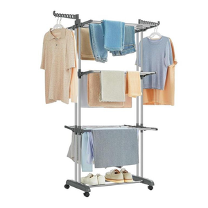 A multi-tiered clothes drying rack with wheels, featuring hangers holding shirts and jeans, towel bars with various towels, and a lower shelf with shoes.