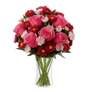 A bouquet featuring pink roses, pink carnations, and red chrysanthemums arranged in a clear glass vase.
