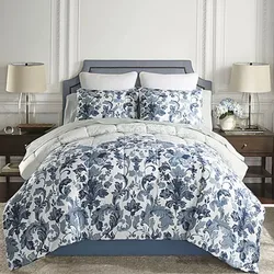 A bed features a blue and white floral comforter set with matching pillow shams, flanked by two wooden nightstands with lamps and decorative items.