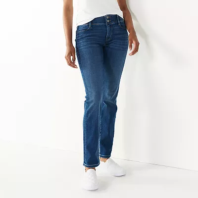 A person is wearing blue denim tummy-control jeans that have a slim fit and a mid-rise waist, paired with white sneakers.