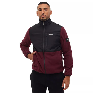 The Bench DNA Men's Sherpa Jacket features a two-tone design with a black top and burgundy lower half. It offers a zip front, high collar, and a Bench logo on the chest and sleeve patch for a casual and stylish look.