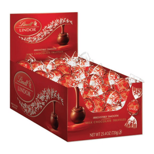 A display box of Lindt Lindor milk chocolate truffles, featuring individually wrapped red and white foil chocolates with the label \“irresistibly smooth.\“ Net weight: 25.4 oz (720g).