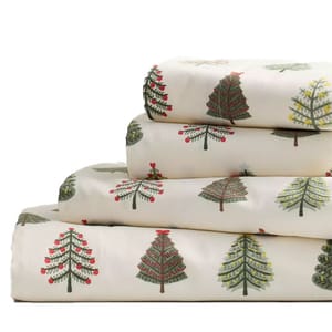 A stack of festive bed sheets with Christmas tree patterns in various designs and colors, displayed on a plain background.