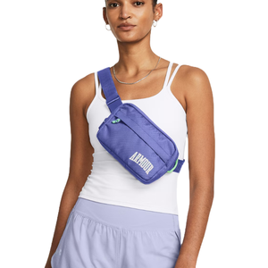 A purple Under Armour crossbody waist bag with a zippered main compartment, adjustable strap, and \“ARMOUR\“ branding; worn over a white tank top with light purple shorts.