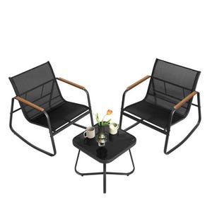 A patio set with two black rocking chairs featuring wooden armrests and a square black side table. The table holds two cups, a coffee pot, and a vase with a flower.