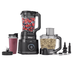 A Ninja multifunction kitchen appliance set includes a blender with berries, a smoothie cup, a food processor with chopped ingredients, and various attachments.