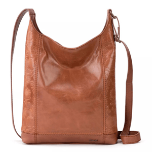 Brown leather crossbody bag with embossed floral details, adjustable strap, and small metal logo plaque near the bottom.