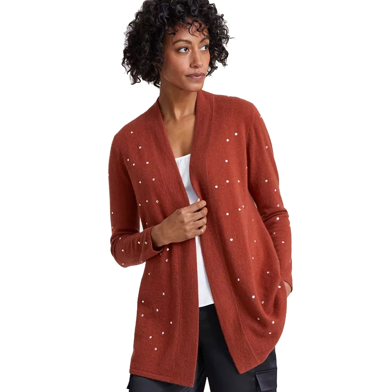 Rust-colored cardigan with white polka dots, featuring an open front design. It's worn over a white top and black pants.