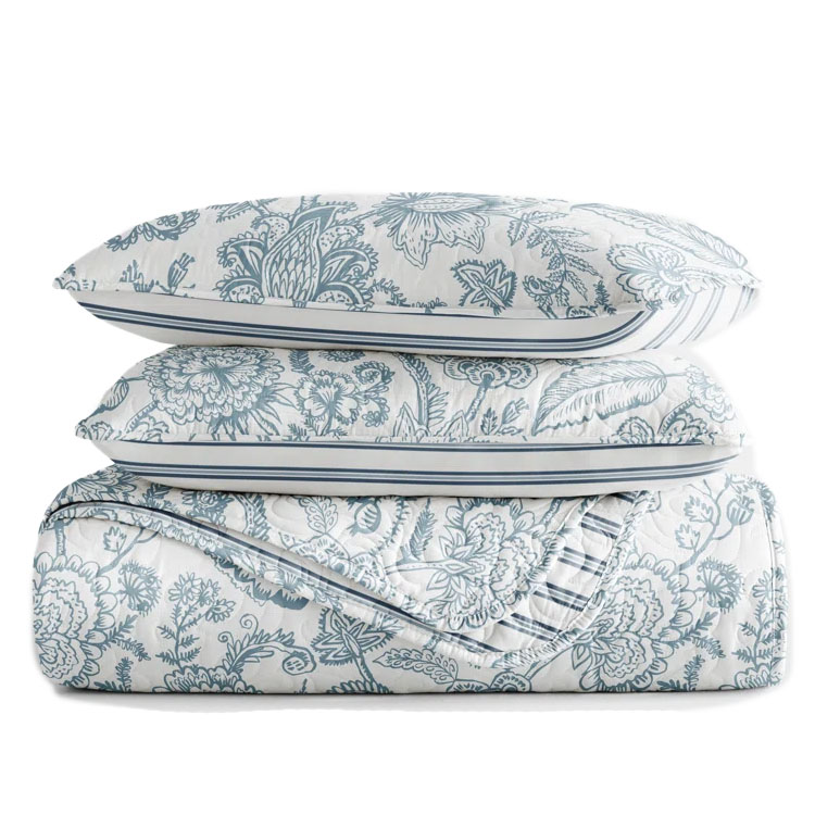 King Reversible Quilt Set features a floral pattern in blue on a white background, including a quilt and two shams. The design is intricate and provides a classic, elegant look for bedding.
