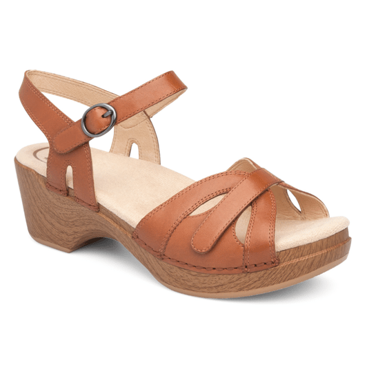 A tan leather sandal with a low wooden-look block heel, featuring crisscross straps and an adjustable ankle strap with a buckle.