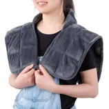 A person is wearing a gray weighted heating pad draped over the shoulders, designed for providing soothing warmth and comfort.