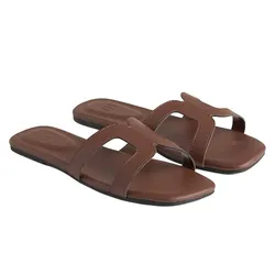 A pair of brown slide sandals with open toes, featuring a cut-out design on the straps and flat soles.
