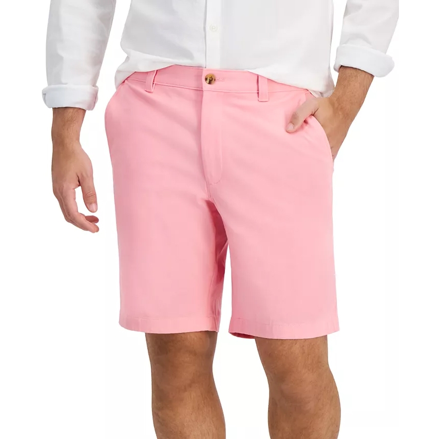 A person wearing pink shorts paired with a white button-up shirt, hands casually in pockets.