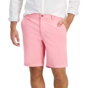 A person wearing pink shorts paired with a white button-up shirt, hands casually in pockets.