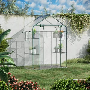 A small greenhouse with a sturdy metal frame and transparent cover stands in a garden, featuring multiple shelves for plants and pots, surrounded by lush greenery and flowers.