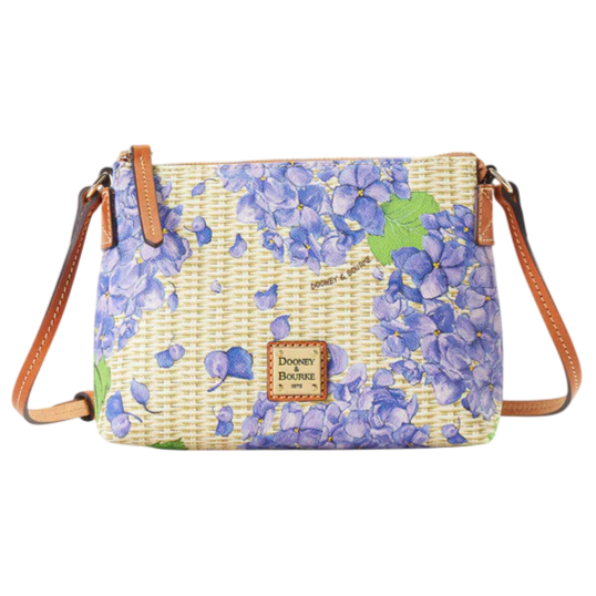 A crossbody bag with a floral design featuring purple hydrangeas, leather straps, and a Dooney & Bourke logo patch.