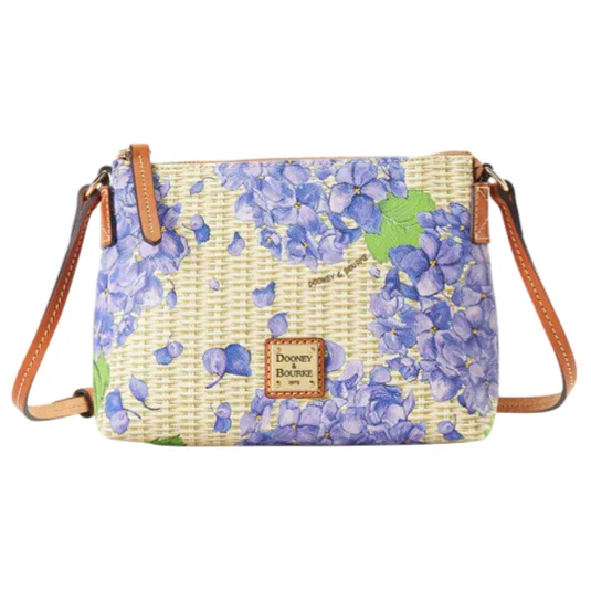 A crossbody bag with a floral design featuring purple hydrangeas, leather straps, and a Dooney & Bourke logo patch.