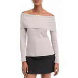 Off-the-shoulder beige ribbed knit top paired with a short black skirt.