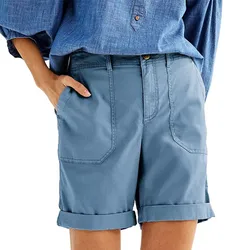 A person wearing cuffed blue shorts with large front pockets and a blue button-down shirt.