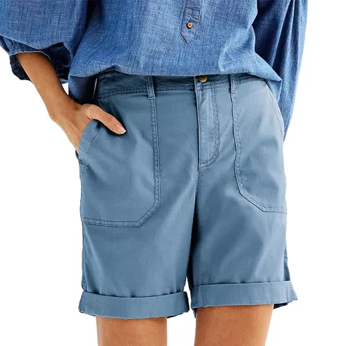 A person wearing cuffed blue shorts with large front pockets and a blue button-down shirt.