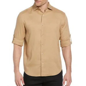 A beige long-sleeve shirt with roll-tab sleeves, button-up front, and a classic collar, worn with black pants.